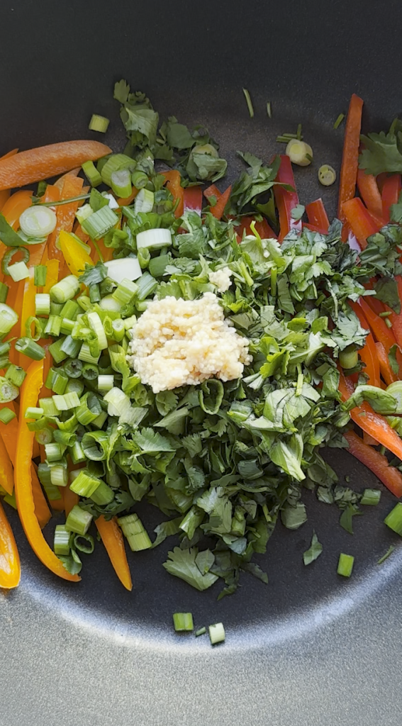 sliced bell peppers with cilantro, basil, and green onions added with garlic minced